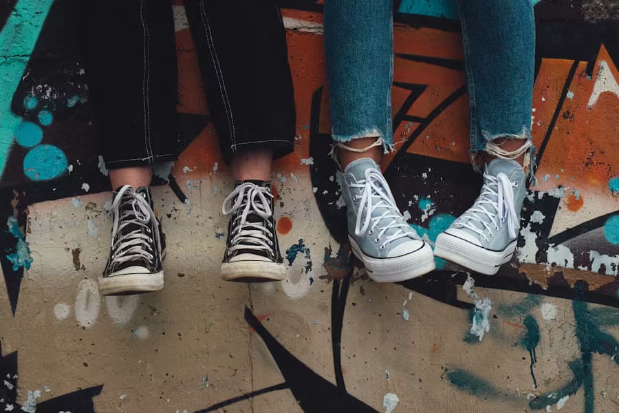 Two teenagers' sneakers dangling over a graffiti-painted ledge, at ease side by side